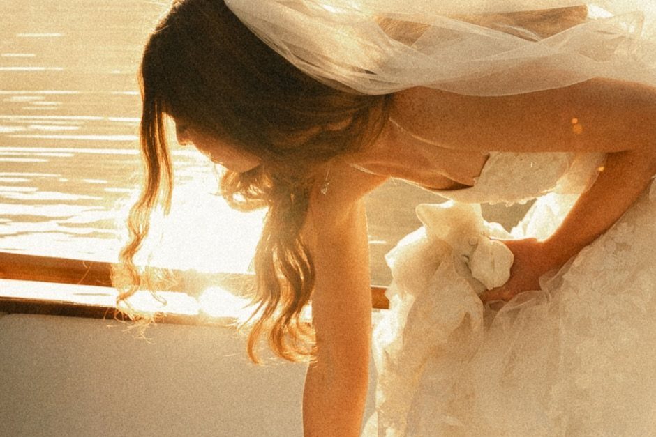 Bride in a white wedding dress and veil glowing in golden sunlight.