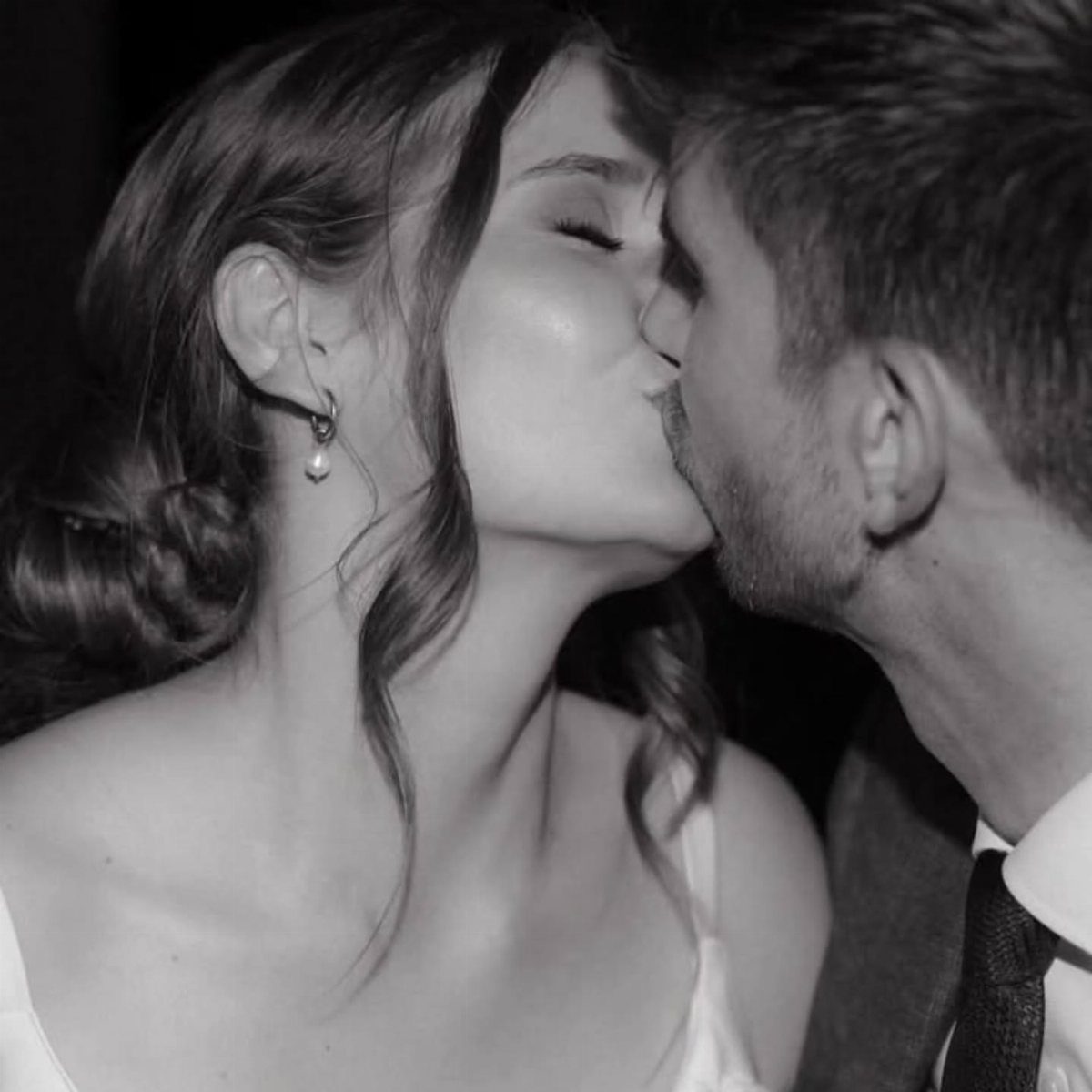 Couple kissing in a romantic black and white close-up portrait.