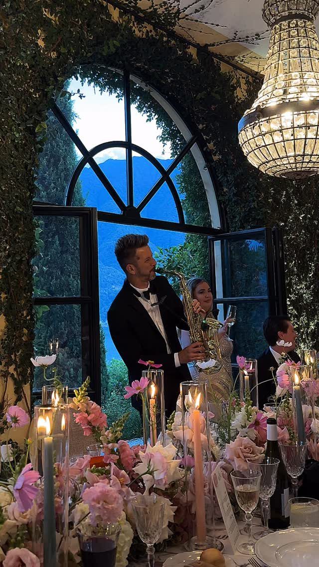 Saxophone player performing at a wedding dinner table with pink floral arrangements